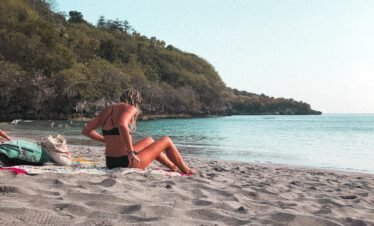 woman in bikini lying on beach sand during daytime